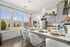 Bright and inviting kitchen space featuring a sleek breakfast bar with elegant place settings, large windows for natural light, and modern grey cabinetry.