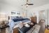 Elegant bedroom showcasing a stylish bed with plush pillows, modern ceiling fan, and chic decor in a cozy, light-filled setting.
