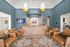 Elegant lobby with modern design featuring chic leather chairs, wooden check-in counter, stylish blue panel walls, and ambient lighting accents.