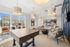 Elegant and inviting lounge area featuring a billiards table, stylish pendant lights, and expansive windows with a poolside view.