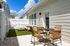 Charming patio with cozy outdoor seating, vibrant green lawn, and bright blue sky accentuating a private fenced area.