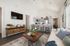 Inviting open-concept living room with elegant decor, featuring a modern kitchen bar with stylish stools, and abundant natural light.