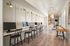 Sleek modern workspace with multiple computer stations, stylish lighting, and elegant decor leading to a cozy lounge area.