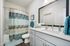 Bright and modern bathroom featuring a spacious vanity, elegant mirror, and stylish shower curtain in soothing blue tones.