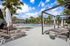 Luxurious apartment complex featuring a sparkling outdoor pool, elegant loungers, and tropical palm trees under a bright blue sky.