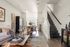 Sleek and modern open-concept living area featuring stylish decor, cozy seating, and a beautifully set dining table, with a staircase leading to the upper level.