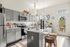 Chic and modern kitchen with sleek gray cabinets, stainless steel appliances, and a bright, sunlit island breakfast bar adorned with stylish decor.
