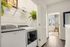 Bright and modern laundry area featuring advanced washer and dryer with elegant shelving and lush greenery, leading into a sunlit room.
