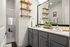 Modern bathroom with dual sinks, sleek gray cabinetry, and stylish wooden shelving accented by greenery and natural decor.