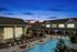Illuminated swimming pool surrounded by cozy lounge chairs at twilight, highlighting serene living.