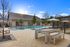 Inviting outdoor pool area with sleek deck furniture, surrounded by lush greenery and a bright, open sky.