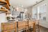 Chic and modern kitchen with elegant shelving, wicker bar stools, and a stylishly set dining counter under contemporary pendant lights.