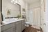 Elegant bathroom with a large mirror, chic vanity, and a modern tub, accented by tasteful decor and bright lighting.