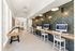 Modern apartment lounge featuring a chic workspace with sleek computers, stylish seating, and a fun shuffleboard table for entertainment.