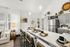 Chic kitchen with modern grey cabinets, sleek stainless steel appliances, and an elegant breakfast bar setup for four guests amidst a bright, open living area.