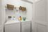 Chic and functional laundry room with modern washer and dryer, elegantly organized with overhead shelving and stylish baskets.