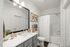 Modern bathroom with elegant vanity, stylish decor, and a cozy white shower curtain creating a serene ambiance.