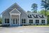 Charming modern home featuring a stylish grey and white exterior with large windows, nestled in a lush, wooded setting.