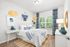 Bright and stylish bedroom featuring modern decor, a cozy bed with blue accents, and large windows allowing natural light to flood in.