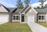 Charming townhouse with modern design, featuring a clean facade, spacious garage, and manicured lawn in a serene neighborhood setting.