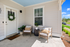 Charming front porch with cozy seating, decorative plants, and a welcoming wreath, perfect for relaxing afternoons.