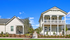 Charming modern duplex with inviting balconies and manicured landscaping under a bright blue sky.