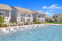 Exquisite community pool paired with modern, elegant townhouses, set against a vibrant blue sky and lush greenery.