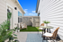 Charming patio with cozy seating and lush greenery, perfect for relaxing and entertaining under a clear blue sky.
