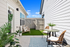 Charming outdoor patio featuring cozy seating with modern decor, lush greenery, and serene ambience under a bright blue sky.