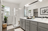 Elegant bathroom featuring a spacious glass shower, dual sinks with sleek gray cabinetry, and modern lighting.