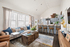 Bright and modern open-concept living room with cozy seating, stylish decor, and a sleek kitchen with bar seating.