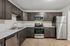 Modern kitchen featuring sleek dark wood cabinets, stainless steel appliances, and elegant marble countertops.
