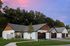 Charming suburban homes with modern design, featuring spacious driveways and nestled in lush greenery under a stunning pink and purple sky.