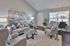 Elegant living room with modern gray furniture, artistic wall decor, and abundant natural light from large windows, creating a cozy atmosphere.