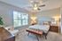 Bright and inviting bedroom with plush carpet, modern ceiling fan, and elegant wooden furniture, perfect for relaxation and comfort.