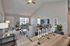 Elegant living area with vaulted ceiling, cozy seating, natural light from large windows, and a stylish dining space.