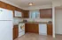 Spacious kitchen with wooden cabinets, white appliances, and beige countertops. A window above the sink adds natural light, creating a warm, inviting atmosphere.