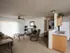 Furnished living area at Oak Court Apartments featuring plush seating, ceiling fan, and access to kitchen and hallway.
