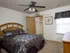 Bedroom with dark patterned bedding, ceiling fan, window, and open closet in Oak Court Apartments.