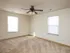 Carpeted bedroom with ceiling fan and two windows letting in natural light at Oak Court Apartments.