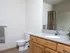 Bathroom at Oak Court Apartments with wood vanity, large mirror, and shower-tub combo with neutral curtain.