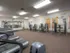 A brightly lit gym with treadmills, weight machines, and mirrors. The room is spacious and organized, conveying a clean and welcoming atmosphere.