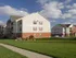 Exterior view of Oak Court Apartments with sidewalk, green lawn, and two-story brick-and-siding buildings.