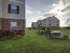 Wide grassy area between apartment buildings at Oak Court, with rock landscaping and evening sky.
