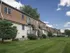 Backside view of multi-story buildings at Harvard Apartments with balconies, brown mansard roofs, and well-maintained lawn space.
