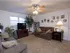 Cozy living room at Harvard Apartments featuring plush carpet, two couches, a ceiling fan, entertainment center, and decorative wall art.