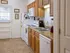 Galley-style kitchen with wood cabinets, white appliances including a microwave and dishwasher, and tile flooring at Harvard Apartments.