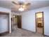 Carpeted bedroom with ceiling fan, two open doorways&mdash;one leading to a closet and the other to a private bathroom with a single-sink vanity.
