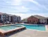 Spacious pool area with hot tub, sundeck, and view of apartment buildings at Embassy Ozark community.