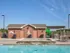 Resort-style swimming pool with hot tub and brick clubhouse in the background at Embassy Ozark Apartments.